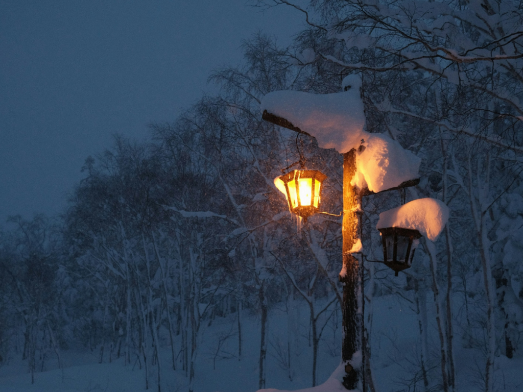 Zimowa scena z oświetloną latarnią symbolizująca ciepło i spokój w zimowej scenerii