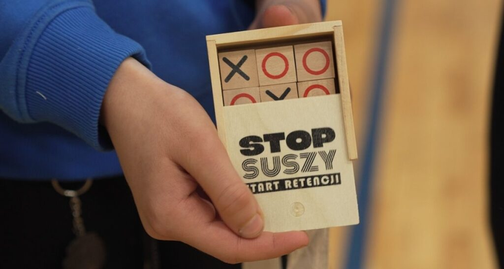 Drewniana gra kółko i krzyżyk z logo Stop Suszy Start Retencji jako materiał edukacyjny
